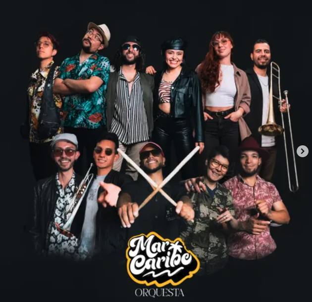 Foto de los nueve integrantes de la Orquesta Mar Caribe sobre fondo negro, con el logotipo de la agrupación